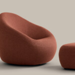 Orange upholstered lounge chair with matching ottoman on neutral background