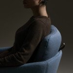woman seated on a blue marien152 lounge chair, the background is brown