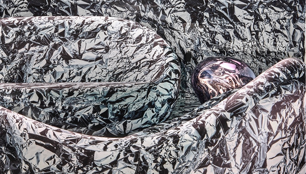Close-up of a sculptural sofa covered in crinkled, reflective silver material.