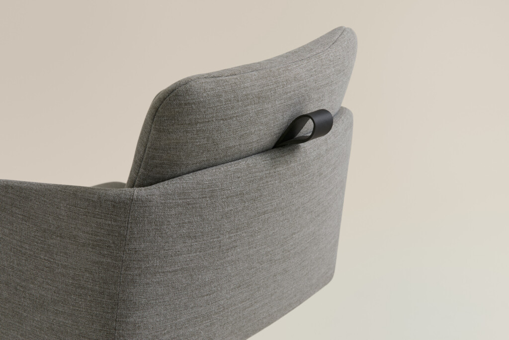 Close-up of gray upholstered chair with integrated black handle on backrest