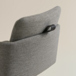 Close-up of gray upholstered chair with integrated black handle on backrest