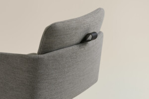 Close-up of gray upholstered chair with integrated black handle on backrest