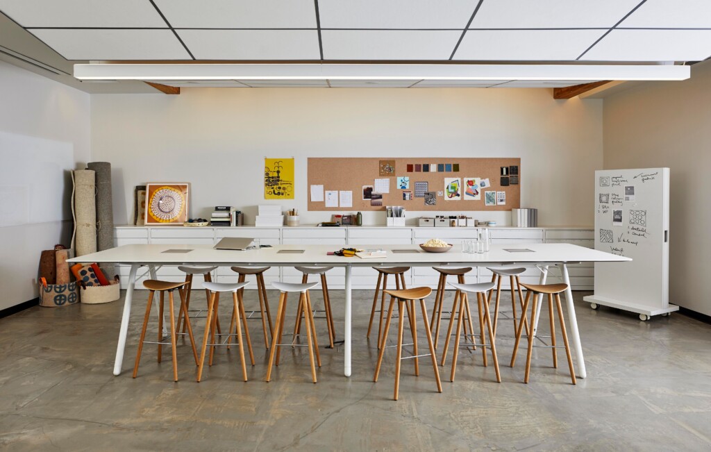 Creative workspace with long tables, stools, and whiteboard in open studio setting