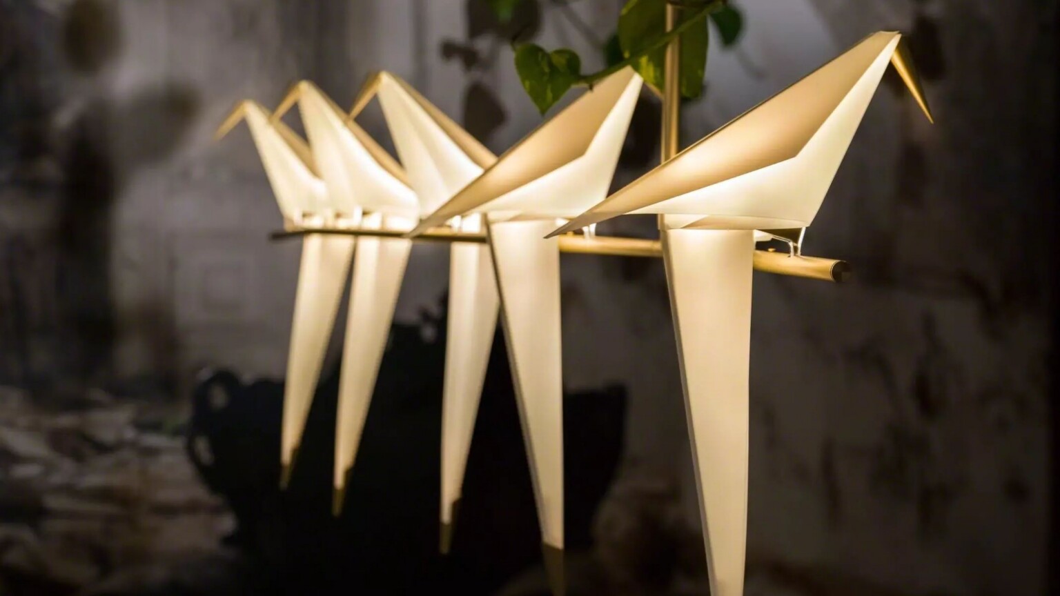 Row of illuminated sculptural lamps with bird‑like shapes