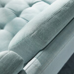 Close-up of light blue upholstered sofa with tufted seat and textured fabric