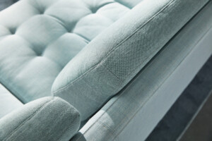 Close-up of light blue upholstered sofa with tufted seat and textured fabric