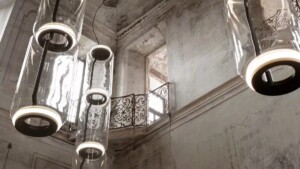 Cylindrical glass lights hanging in a weathered interior with ornate railings