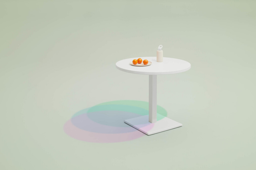 Round white pedestal table on a light green background with a small plate of oranges and a bottle on top.