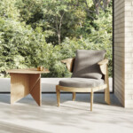 Minimalist seating area with a wooden armchair and side table placed by a large window overlooking greenery.