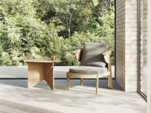 Minimalist seating area with a wooden armchair and side table placed by a large window overlooking greenery.