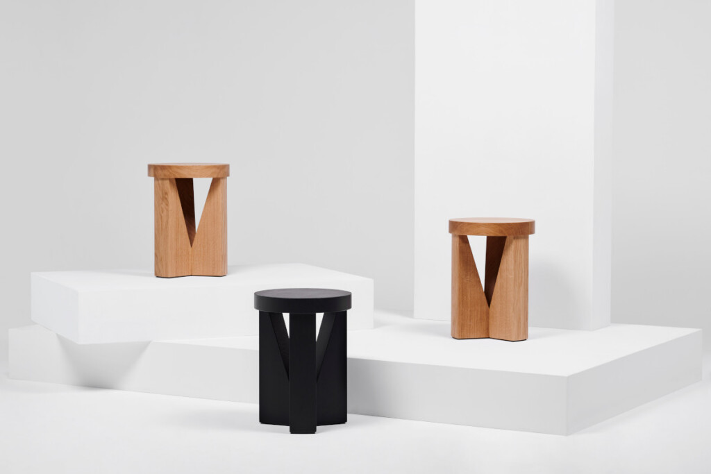 Three stools displayed on white platforms, shown in natural wood and black finishes.