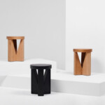 Three stools displayed on white platforms, shown in natural wood and black finishes.