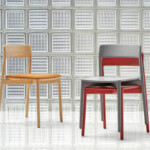 Two chairs displayed in front of a glass block wall, one in natural wood with a tan seat and one in gray and red.