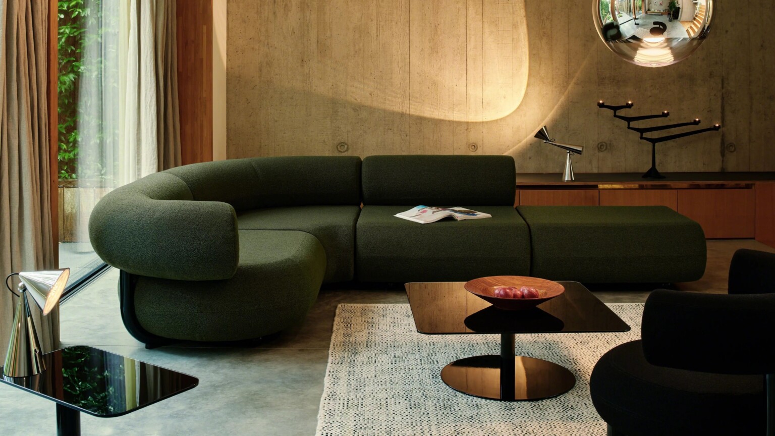 Living room featuring a curved green sofa, low tables, and accent lighting