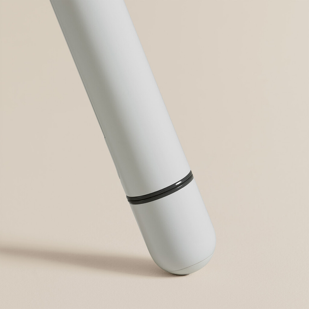 Close-up of white metal table leg with black detail on neutral background