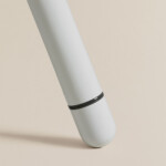 Close-up of white metal table leg with black detail on neutral background