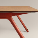 Wood table with red angled metal legs on neutral background