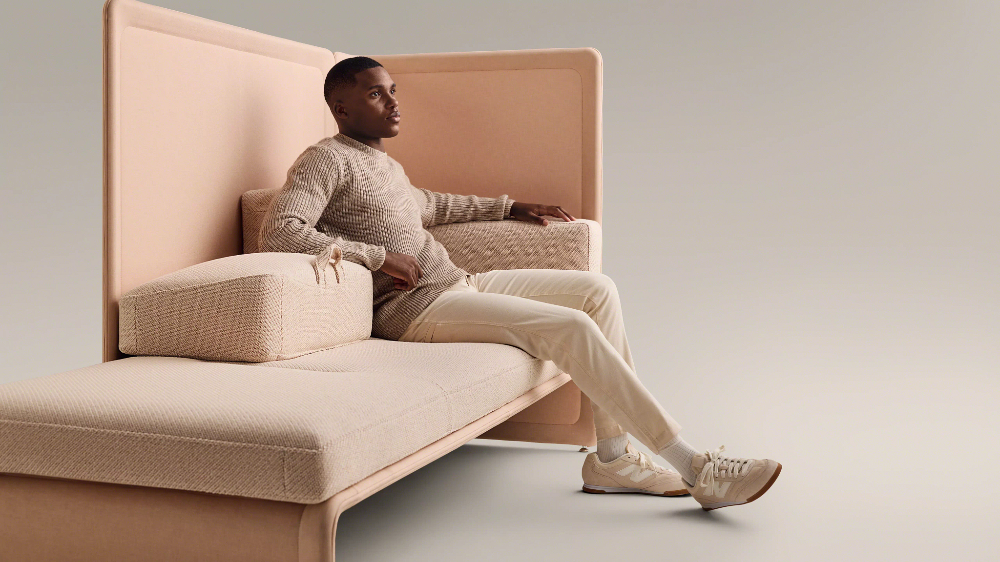 Man seated on modern high-back upholstered lounge seating against neutral background