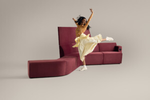 Woman posing on modern upholstered lounge seating against neutral background