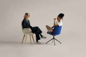 Two women smiling at each other while seated in upholstered chairs