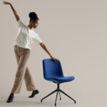 Woman posing with upholstered blue chair without armrests