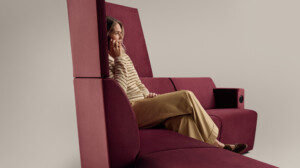 Woman sitting in modern upholstered lounge seating against neutral background