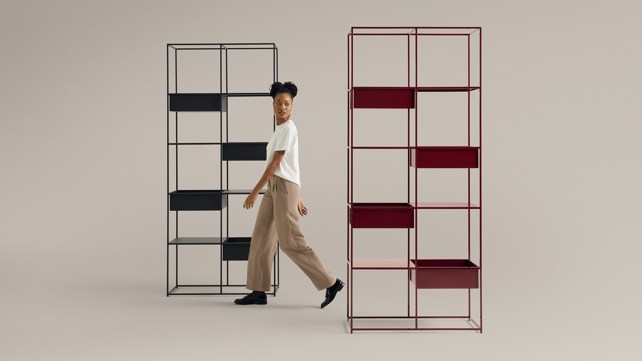 Woman walking between modern open-frame shelving units on neutral background