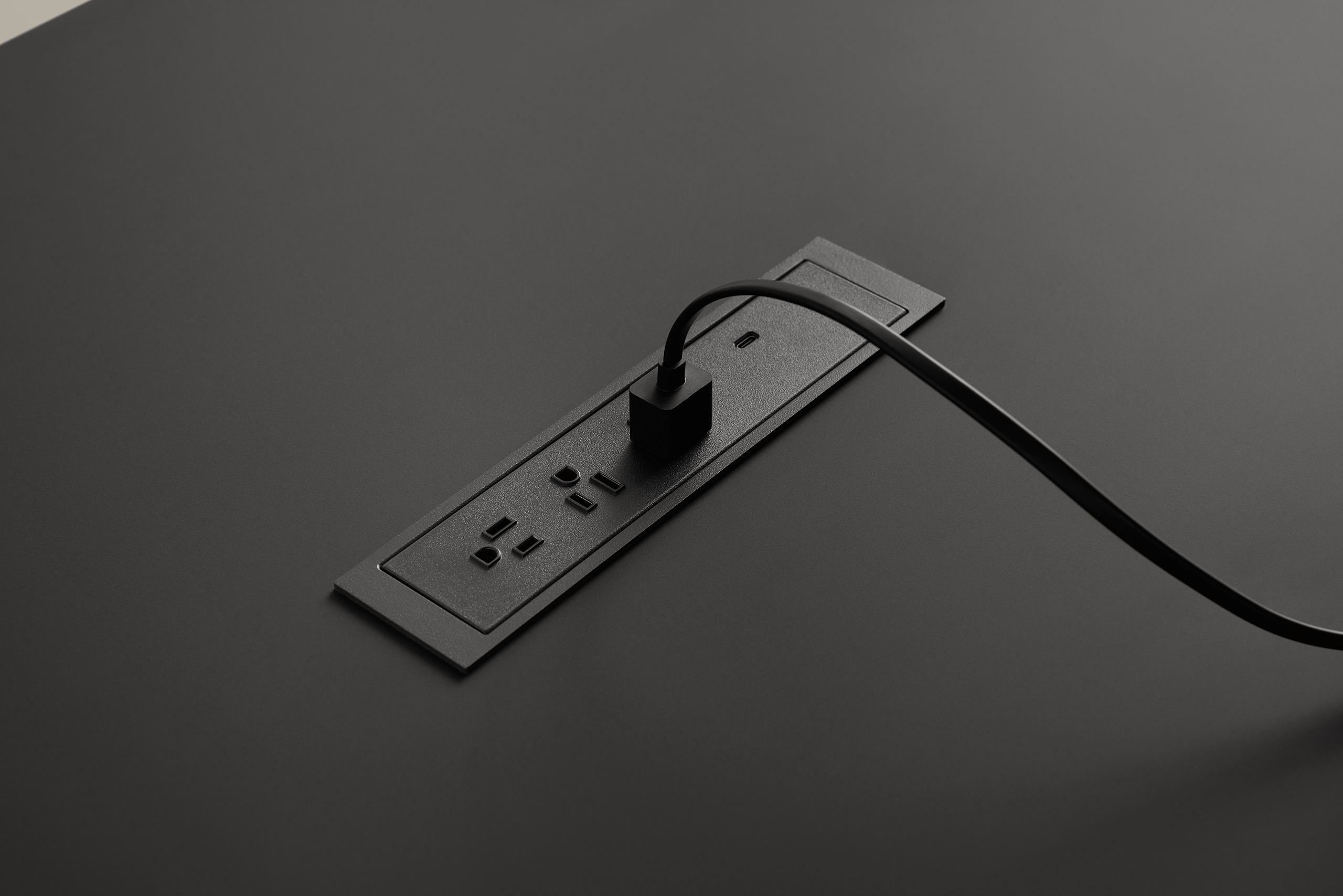 Close-up of black table with integrated power outlet