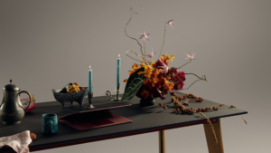 Black table styled with floral arrangement, candles, decorative objects, and laptop
