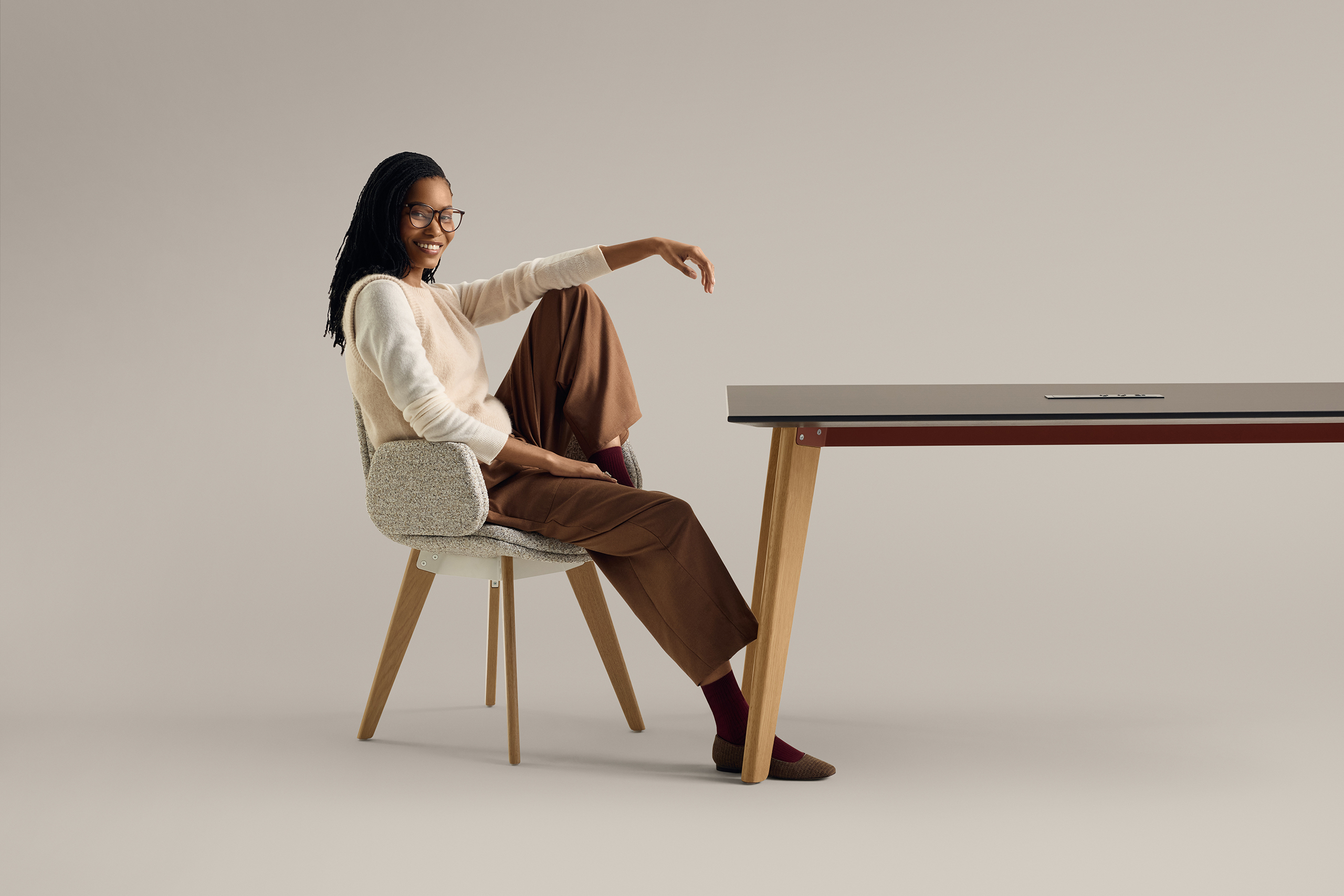 Woman sitting in upholstered chair at modern table against neutral background