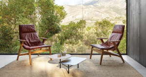 Modern lounge with two red chairs, two coffee tables, and a landscape backdrop.