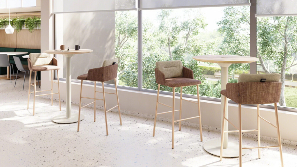 Modern café-style workspace with upholstered bar chairs, round tables, and large windows