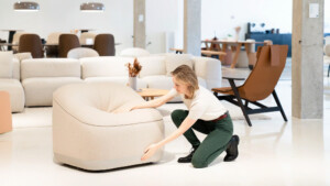 Person adjusting modern upholstered lounge chair in contemporary showroom.