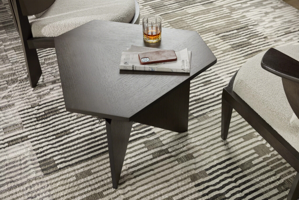 Close-up of geometric wood side table with newspaper, phone and drink on top