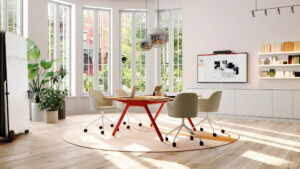 Modern collaborative meeting room with table, rolling chairs, digital display, and mobile whiteboard