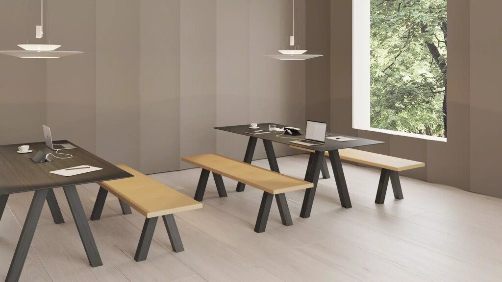 Modern interior with sets of black tables and wooden benches next to a large window showing a natural environment