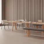 Minimalist dining setup with a long wooden table, bench, and matching chairs near a bright window.