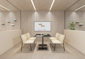 Minimalist meeting room with a table and four cream chairs facing a screen in the middle of the room.