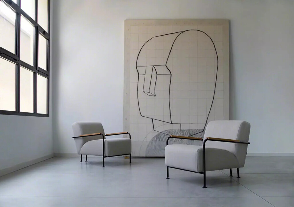 Two gray lounge sofas with an abstrast painting between them set in a modern interior space.