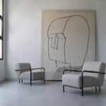 Two gray lounge sofas with an abstrast painting between them set in a modern interior space.