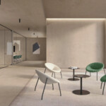 Bright modern lounge area featuring four lounge chair and small round tables near a large window