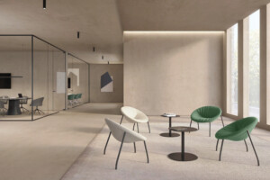 Bright modern lounge area featuring four lounge chair and small round tables near a large window